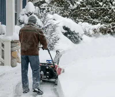 Residential snow removal technician using a snow blower to clear a home driveway and walkway in Little Rock, AR